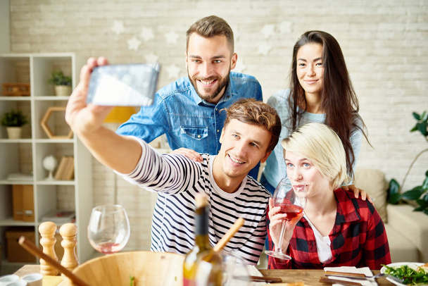 Portrait of happy friends taking selfie at dinner table while celebrating festive occasion - Zdjęcie, obraz