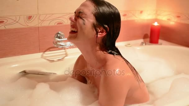 Beautiful young woman relaxing in jacuzzi hot tub spa resort, by romantic candles background. Immersed in the foam, cries and laughs. - Felvétel, videó