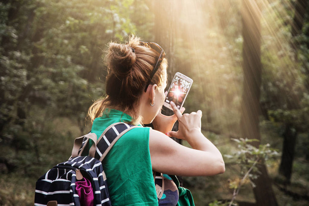 Young caucasian brunette woman takes photo in the forest - Fotó, kép