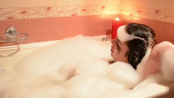 Mulher bonita relaxante em jacuzzi banheira de hidromassagem spa resort, por velas românticas fundo. Imerso na espuma, chora e ri
. - Filmagem, Vídeo