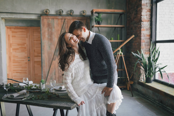 Newlyweds laughing and kissing on the kitchen table - Valokuva, kuva