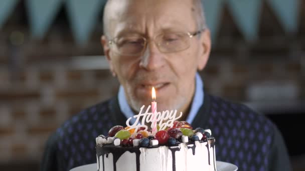 Close-up of senior man blowing candle on cake - Video