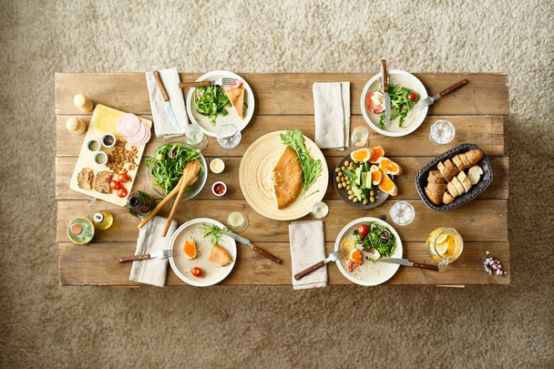 Yllä näkymä puinen illallinen pöytä puoli-syödään ruokia jäljellä, ei ihmisiä
 - Valokuva, kuva