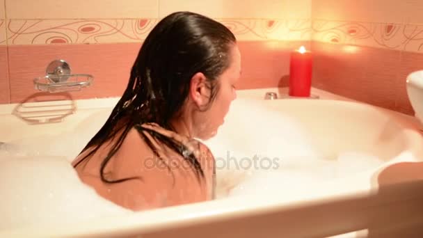 Beautiful girl taking a bubble bath with a glass of wine. A large white bath and joy on his face. relaxation concept - Footage, Video