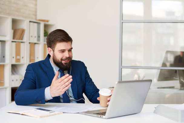 Портрет усміхненого бородатого бізнесмена, який розмовляє з партнером через ноутбук через зустріч у відео чаті
 - Фото, зображення