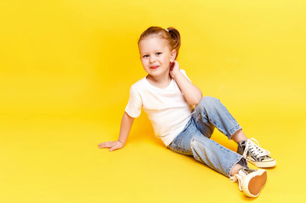 Adorable stylish girl posing on yellow background - Фото, зображення