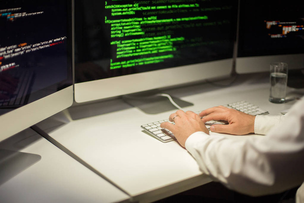 Κοντά shot της αγνώριστος προγραμματιστής τυλιγμένη σε κωδικοποίηση ενώ κάθεται στο γραφείο - Φωτογραφία, εικόνα