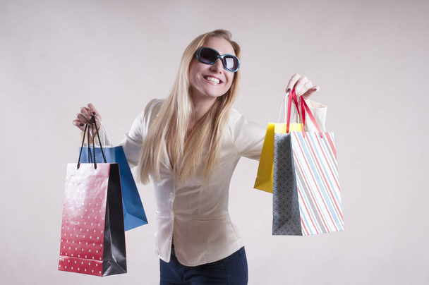 woman with a jacket in sunglasses with packages for purchases studio - Фото, изображение