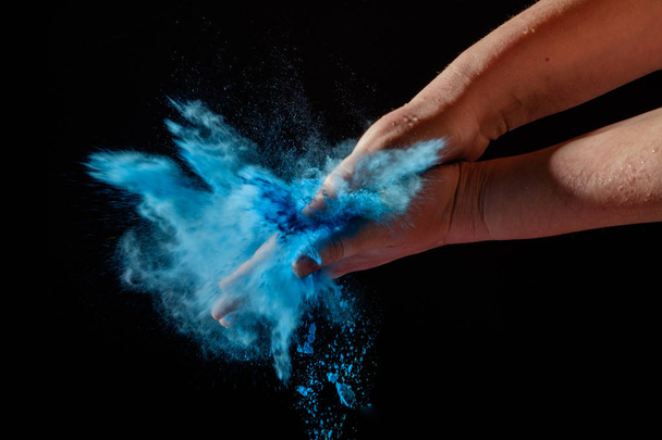 Closeup shot of female hands holding colorful dry paint at Holi Festival. Splash of blue color paint. - Fotó, kép