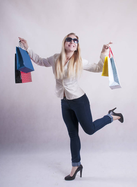 Nainen, jolla on takki aurinkolaseissa paketteja ostoksille studio
 - Valokuva, kuva