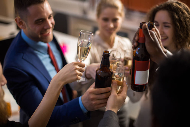 junge Büroangestellte feiern Firmenevent, klimpern mit Gläsern mit alkoholischen Getränken und lächeln fröhlich - Foto, Bild