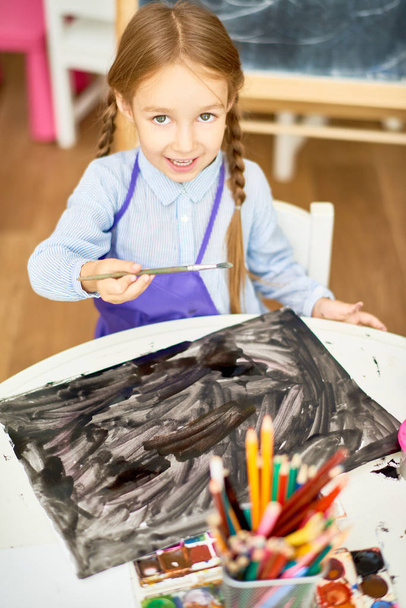 Portrait of adorable little girl painting pictures on Halloween enjoying art lesson in development school - Photo, Image