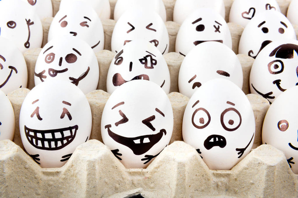 Eieren met getekende cartoon gezichten in lade. - Foto, afbeelding