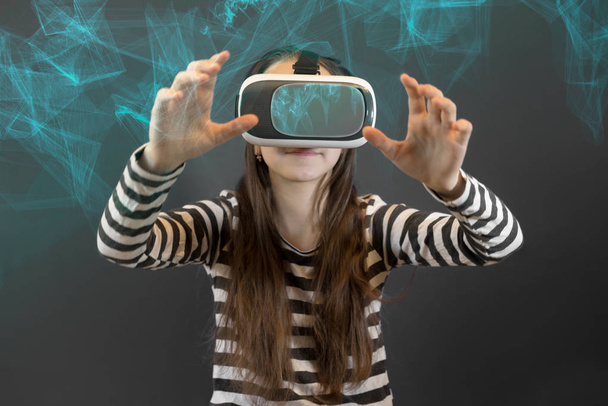 Teenager caucasian girl looking at Virtual Reality Glasses over abstract futuristic modern technology background with lines. Virtual reality, vr box. Studio, indoors. - Photo, Image