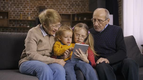 Οικογένεια με τη χρήση tablet pc στον καναπέ μαζί στο σπίτι - Πλάνα, βίντεο