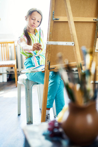 Tam uzunlukta şövale önünde oturan ve natürmort Resim Sanat stüdyosu oluşturma yetenekli küçük kız portresi - Fotoğraf, Görsel