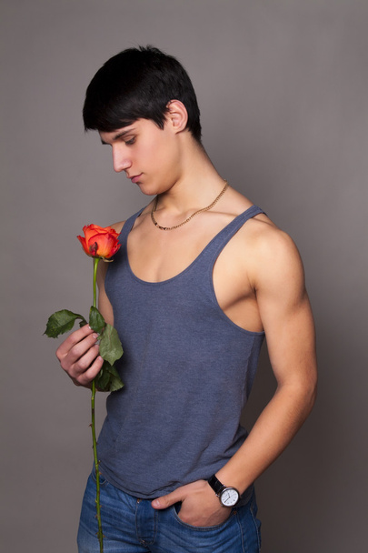 Muscular man with a rose in hands - Φωτογραφία, εικόνα
