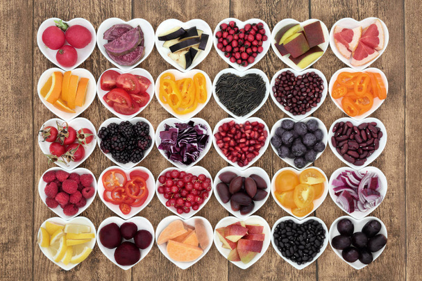 Healthy diet food concept with super health promoting properties in heart shaped bowls, high in antioxidants, anthocyanins, vitamins and minerals on rustic wood background. Top view. - Photo, Image
