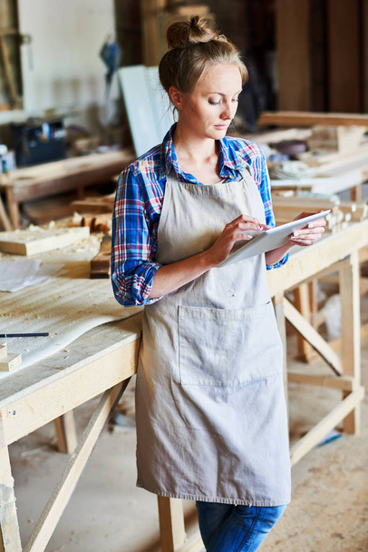 Πορτρέτο της νεαρής γυναίκας, χρησιμοποιώντας ψηφιακό tablet στο κατάστημα μοντέρνα ξυλουργικής - Φωτογραφία, εικόνα