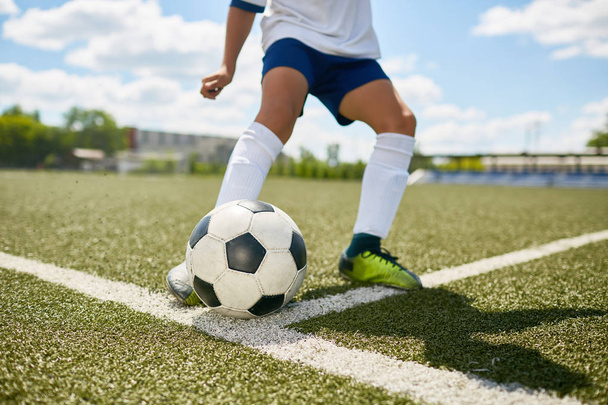 Closeup portret van onherkenbaar tiener schoppen de bal tijdens voetbal praktijk in veld buitenshuis - Foto, afbeelding