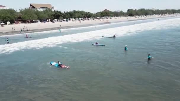 Surfers starting a surfing ride together in the blue ocean, having fun during a sunny day on an active sports vacation, wearing neoprene suits. Video - Filmmaterial, Video