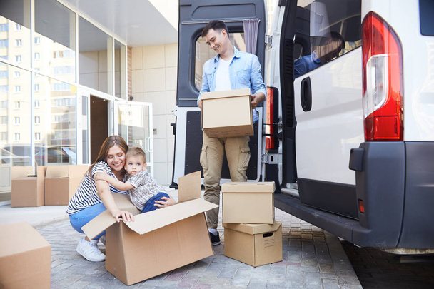 Πορτρέτο της αγάπης νεαρή οικογένεια με παιδάκι φόρτωσης κουτιά από χαρτόνι σε κινητά van σε εξωτερικούς χώρους - Φωτογραφία, εικόνα