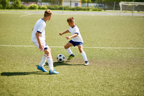 Портрет двух мальчиков, играющих в футбол во время юношеской командной тренировки в поле
 - Фото, изображение