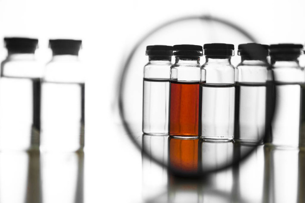 Medical ampoules under a magnifying glass on a white background - Photo, Image