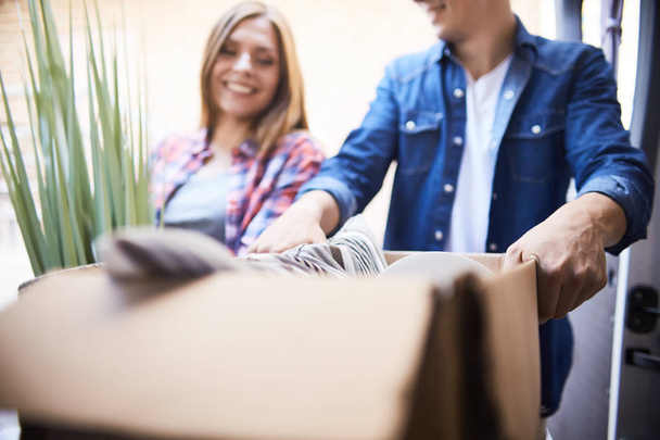 Portrait of smiling man and woman putting cardboard box into moving van - Photo, Image