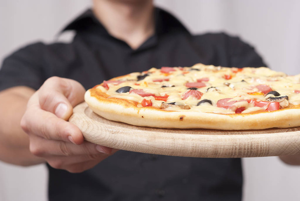 Чоловік тримає піцу
 - Фото, зображення
