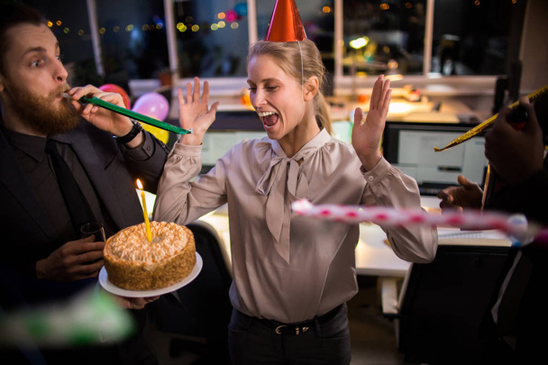 Firmenmitarbeiter feiern Geburtstag einer fröhlichen Kollegin mit Kuchen und Partyhörnern im Büro - Foto, Bild