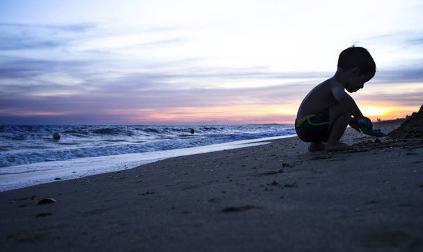 Силует хлопчика, який грає на пляжі під час чудового
 - Фото, зображення