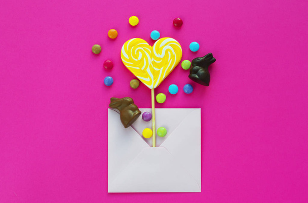 pirulito em forma de coração amarelo, coelho de chocolate e doces presentes
 - Foto, Imagem