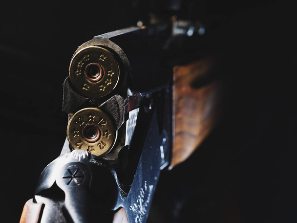 Κοχύλια κυνηγετικό όπλο και πυροβόλησε σε μαύρο φόντο. Φορτωμένο με σφαίρες κυνηγός τουφέκι. - Φωτογραφία, εικόνα