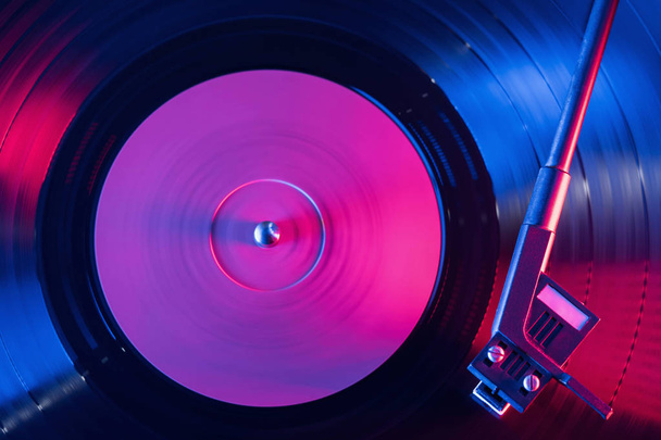A retro-styled spinning record vinyl player. Vintage shot of old gramophone, playing close up. Beautiful colorful movie. Neon violet led light. - Foto, immagini