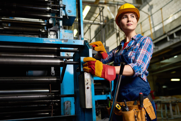 Porträt einer Fabrikarbeiterin beim Aufbau von Maschineneinheiten, die in modernen Anlagen selbstbewusst wegschauen - Foto, Bild