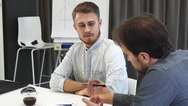 Nuori liikemies kuuntelee kypsää kollegaansa tapaamisen aikana
 - Materiaali, video