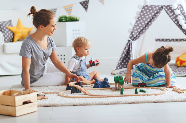 familia madre e hijos jugar un juguete ferroviario en playroo
 - Foto, Imagen