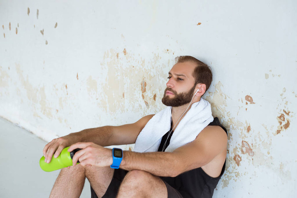 Hombre en forma tomando un descanso de hacer ejercicio en el gimnasio y beber agua
.  - Foto, imagen