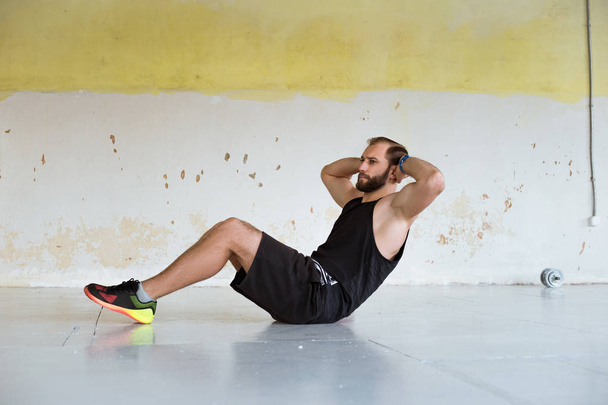 молодой спортивный человек делает упражнения на полу в спортзале
 - Фото, изображение