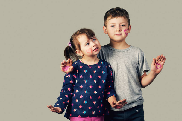 Brother and sister with painted hearts on the face and hands . Happy family - Photo, image