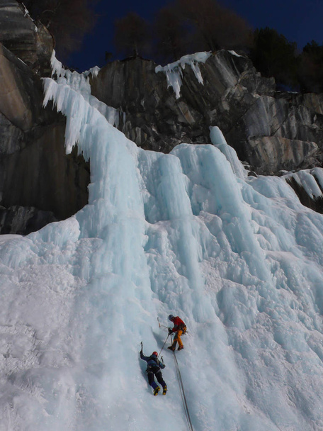 スイス アルプスの急な凍った滝に男性アイスクライマー - 写真・画像