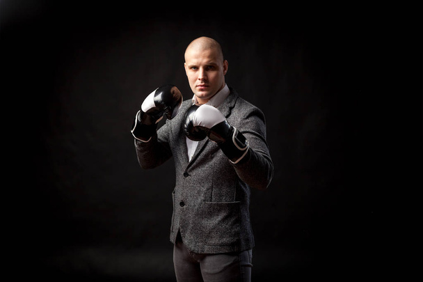 白いシャツ、グレーのスーツの若い男マネージャー、真剣にボクシングの手袋に見える、黒いボクシング分離された背景 - 写真・画像