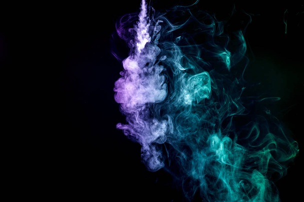 Fumée dense multicolore de couleurs violettes et vertes sur un fond isolé noir. Contexte de la fumée vape
 - Photo, image