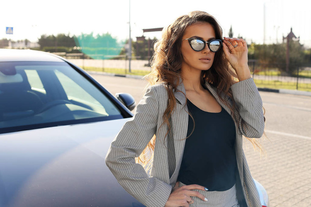 fashion outdoor photo of beautiful sexy woman in elegant clothes posing in luxurious car - Fotó, kép