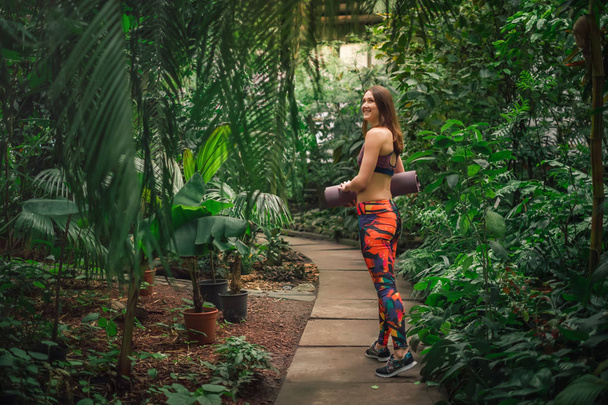 Positiivinen naispuolinen joogaohjaaja poseeraa kasvihuoneessa
 - Valokuva, kuva
