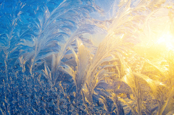 Ψυχρός μοτίβα πάνω στο γυαλί κατά τη διάρκεια του ηλιοβασιλέματος. - Φωτογραφία, εικόνα