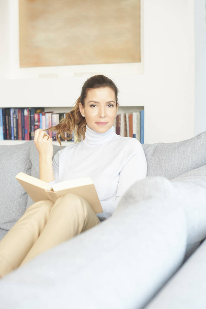 Beautiful middle aged woman reading a good book at home. - Foto, Bild