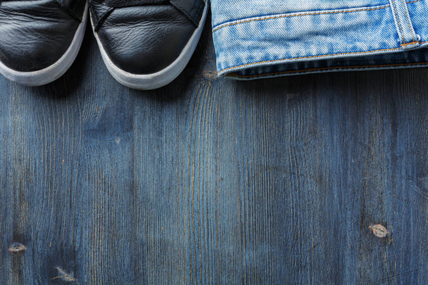 Top view of wooden surface with sneakers and jeans. Casual concept - Фото, изображение