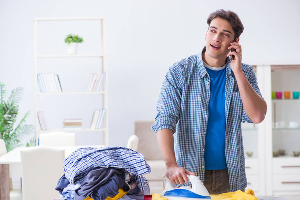 Young man husband doing clothing ironing at home - Foto, Bild